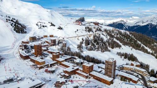 Vue aérienne de la station de ski Les Chalets d'Aline dans les Alpes françaises avec montagnes enneigées et village alpin