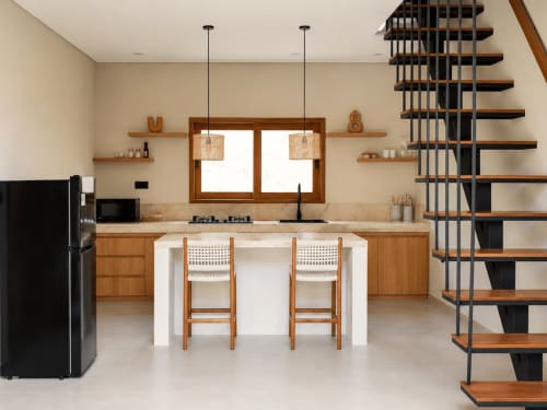 Cocina y comedor moderno en villa Oasis Dune Villas con muebles de madera, isla central y escalera en Lombok