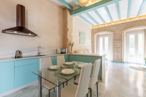 Cocina y comedor modernos en el Apartamento Triana Procurador 2, Sevilla, con gabinetes turquesas, mesa de cristal y