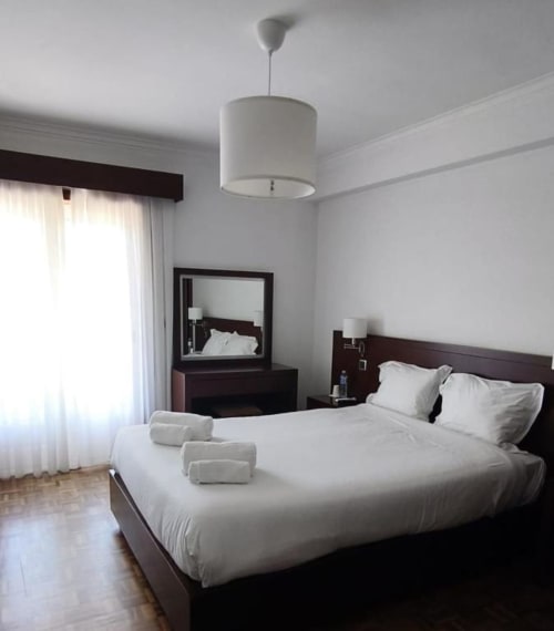Deluxe double room at Hotel Slow Stay in Esposende with white bedding, dark wood furniture, and modern pendant lighting