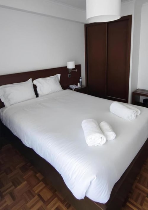 Deluxe Double Room at Hotel Slow Stay in Esposende with white bedding, rolled towels, and dark wood furnishings