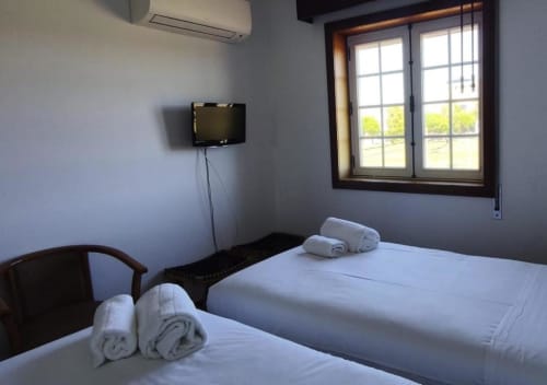 Twin bedroom at Hotel Slow Stay in Esposende with two beds, wall-mounted TV, and garden view window