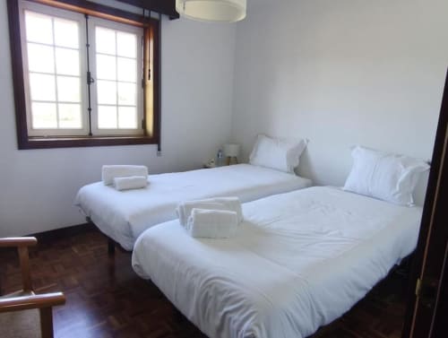 Twin bedroom at Hotel Slow Stay with two single beds, white linens, wooden window frame, and hardwood flooring in Esposende