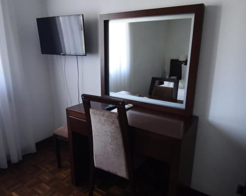 Hotel Slow Stay twin room with dark wooden desk, framed mirror, wall-mounted TV, and chair in Esposende