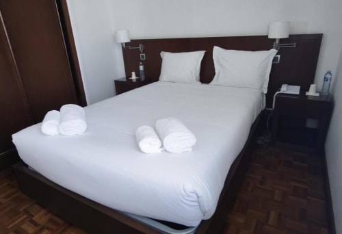 Twin bed with white linens and rolled towels at Hotel Slow Stay, Esposende, Portugal