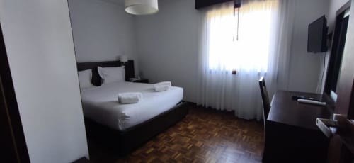 Twin bedroom at Hotel Slow Stay in Esposende with white bedding, dark wood furniture, parquet flooring, and garden view from