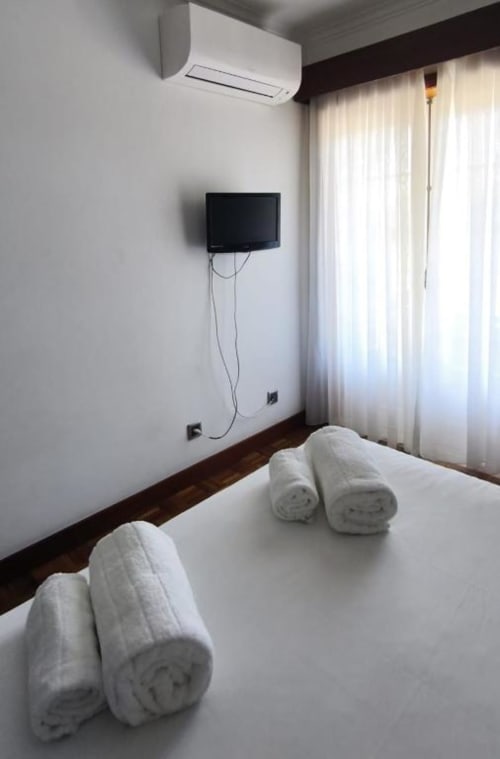 Deluxe Double Room at Hotel Slow Stay, Esposende with rolled towels, wall-mounted TV, AC unit, and sheer curtains