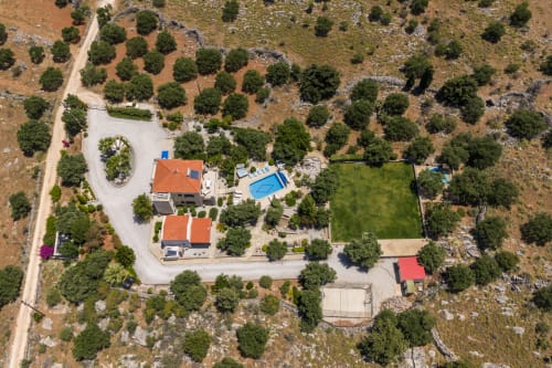 Villa Freedom aerial view with pool, red-roofed buildings, and surrounding olive groves in Kokkino Chorio, Crete