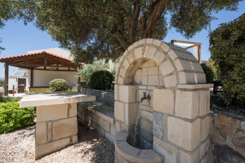 Ancient stone well at Villa Freedom, a Cretan BnB in Kokkino Chorio with olive tree and courtyard structures