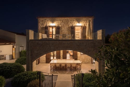 Villa Freedom nighttime exterior, Kokkino Chorio Crete. Stone archway with illuminated upper terrace and dining courtyard.