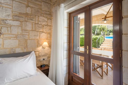 Bedroom with stone walls and glass doors opening to terrace at Villa Freedom, Kokkino Chorio, Crete