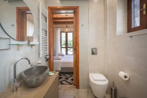 Modern bathroom at Villa Freedom with stone sink, wooden accents, and view to bedroom in Crete