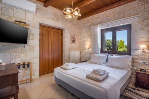 Luxurious bedroom at Villa Freedom in Kokkino Chorio, Crete with stone walls and modern amenities