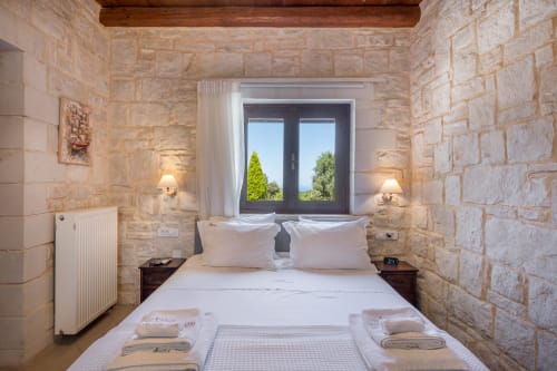 Luxury bedroom at Villa Freedom in Kokkino Chorio, Crete with stone walls, double bed, and garden views