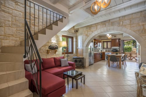 Villa Freedom open-plan living area with red sofa, stone archways, and kitchen in Crete