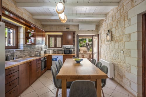 Modern kitchen and dining area at Villa Freedom in Kokkino Chorio, Crete with wooden table and stone walls