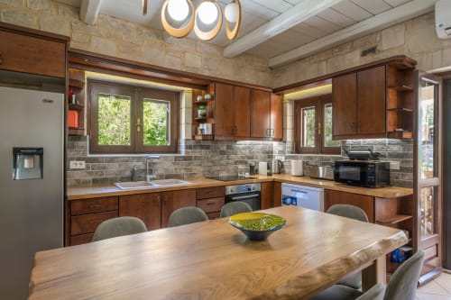 Modern kitchen and dining area at Villa Freedom in Crete with wooden cabinets, stone backsplash, and natural light