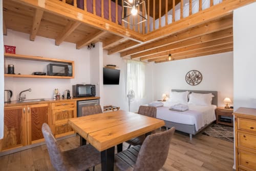 Modern loft bedroom at Villa Freedom in Crete with wooden beams, kitchenette, and mezzanine level