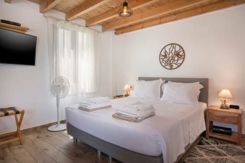 Bright bedroom at Villa Freedom in Crete with wooden beams, gray bed, and modern amenities