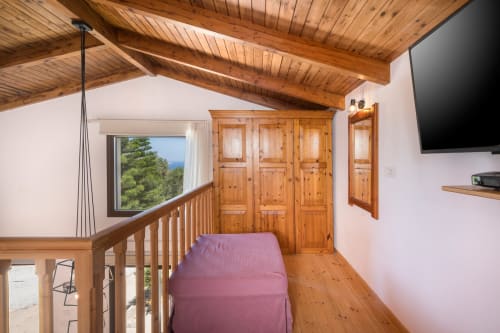 Spacious loft bedroom at Villa Freedom, Crete with exposed beams, wooden wardrobe, and sea views