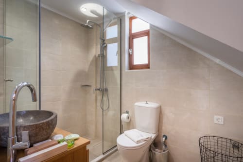Modern bathroom at Villa Freedom Crete with stone basin sink, walk-in shower, and sloped ceiling