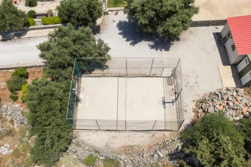 Aerial view of tennis court at Villa Freedom, Kokkino Chorio, Crete, surrounded by Mediterranean vegetation