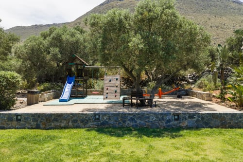 Children's playground with slide and climbing wall at Villa Freedom, surrounded by olive trees in Kokkino Chorio, Crete