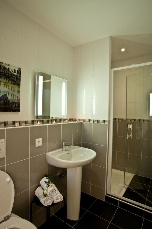 Salle de bain moderne avec lavabo sur colonne, miroir éclairant et douche à l'italienne au Jardin de la Reyssouze