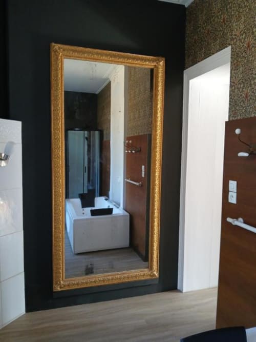 Salle de bain moderne avec miroir encadré d'or ouvragé à la villa Le château de Mons Boubert, parquet en bois