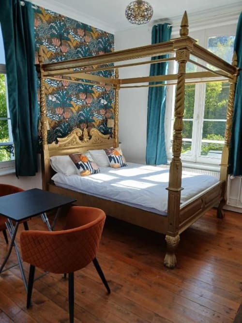 Lit à baldaquin luxueux dans la chambre élégante de la villa Le château de Mons Boubert, avec cadre en bois orné et papier peint bleu-vert