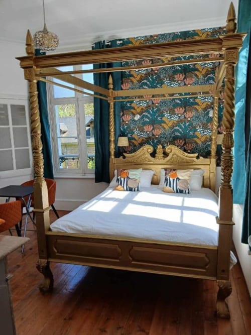 Lit à quatre colonnes doré et orné avec papier peint floral turquoise dans la chambre de la villa Mons-Boubert