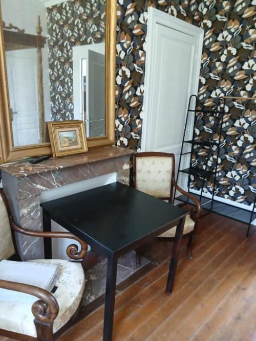 Élégante salle à manger du château de Mons Boubert avec table en marbre, chaises en bois, miroir orné et papier peint floral foncé