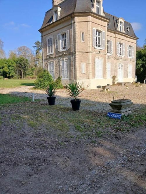 Château de Mons Boubert, villa en brique aux toits mansardés et volets blancs, sur parc paysagé avec potées fleuries et
