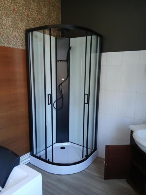 Cabine de douche d'angle contemporaine aux vitres transparentes et cadre noir dans la salle de bain de la villa Le château de Mons Boubert