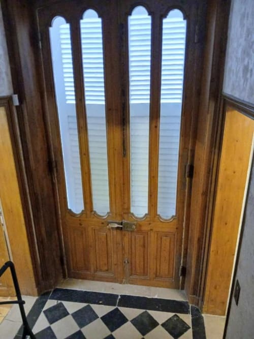 Portes doubles en bois avec vitres et volets à l'entrée de la villa Le château de Mons Boubert, sol à carreaux visible