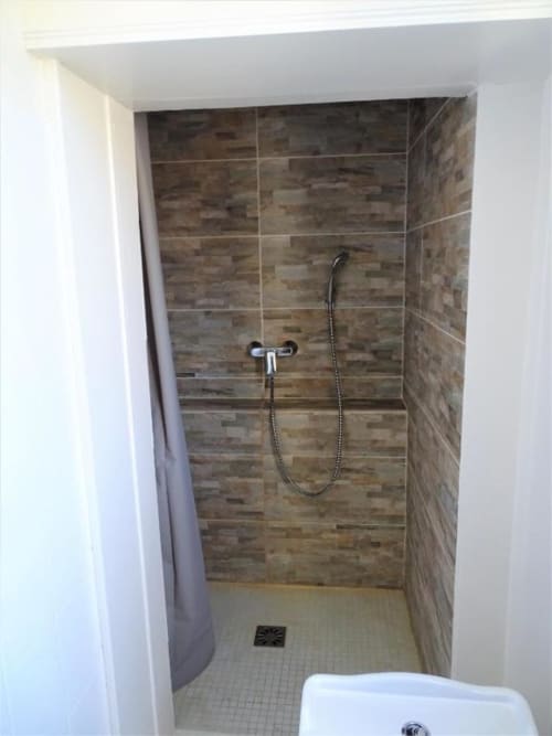 Salle de douche moderne avec carrelage aspect bois et pommeau de douche manuel à la villa Le Château de Mons Boubert
