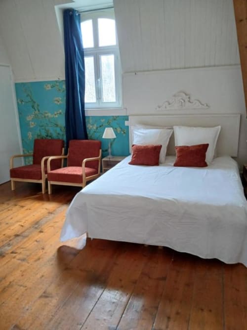 Chambre élégante du château de Mons Boubert avec lit blanc, accents bordeaux, parquet et élément turquoise