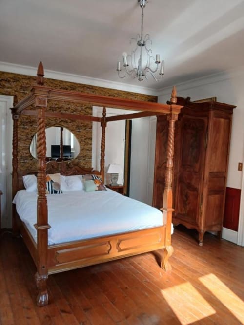 Élégant lit à quatre colonnes en bois avec draps blancs dans une chambre du château de Mons Boubert, avec parquet