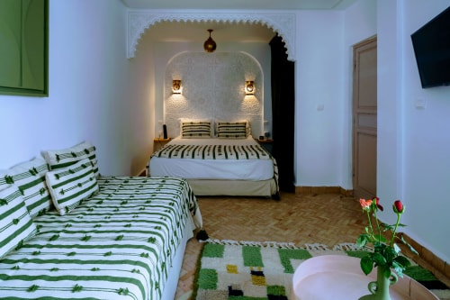 Chambre de l'Hôtel Dabachi à Marrakech avec lit jumeaux, alcôve, literie rayée verte et décor marocain traditionnel