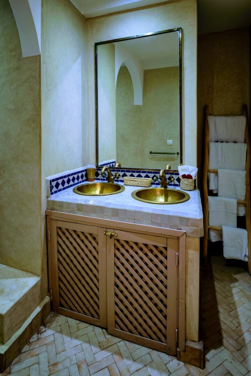 Salle de bains luxueuse avec double vasque en laiton et miroir à cadre noir à l'hôtel Dabachi de Marrakech