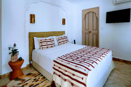 Chambre d'hôtel marocain à Dabachi Marrakech avec literie rayée, tête de lit dorée et décoration traditionnelle