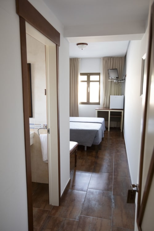 Habitación doble Hostal Atalaya en Minas de Riotinto con cama, escritorio, baño, TV y aire acondicionado
