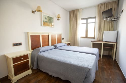 Habitación doble en Hostal Atalaya de Minas de Ríotinto con camas gemelas, TV, muebles de madera y comodidades modernas