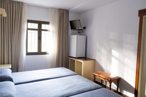 Habitación triple en Hostal Atalaya de Minas de Ríotinto con camas gemelas, TV, refrigerador y luz natural