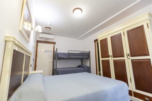 Habitación cuádruple en Hostal Atalaya de Minas de Ríotinto con cama doble, literas y armarios de madera