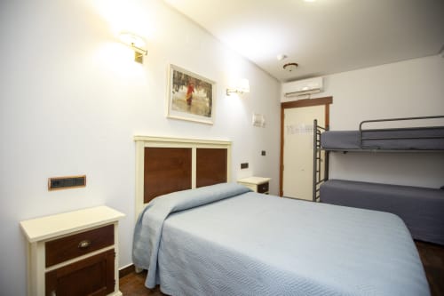Habitación cuádruple en Hostal Atalaya de Minas de Ríotinto con cama de matrimonio, literas y muebles de madera