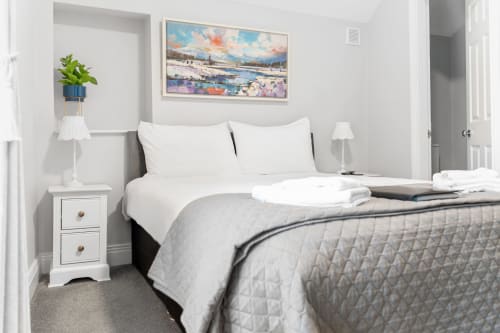 Modern double bedroom at Madeline's Accommodation, Wicklow with mountain view artwork, white bedding, and contemporary