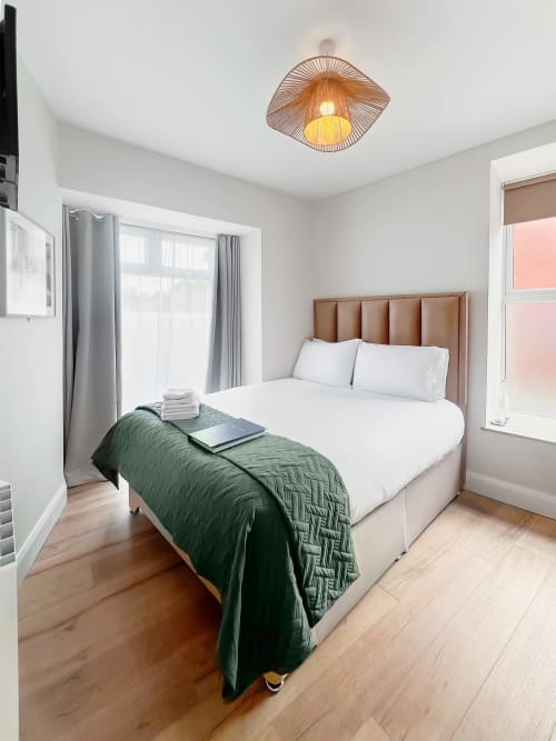 Bright double bedroom at Madeline's Accommodation in Wicklow with tan leather headboard, white bedding, green throw, and