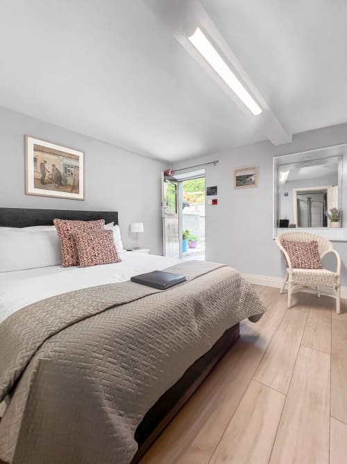 Modern double bedroom at Madeline's Accommodation in Wicklow with mountain view, black bed, wicker chair, and en-suite