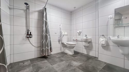 Modern bathroom at Madeline's Accommodation in Wicklow with white tiles, double sink, toilet, and shower area